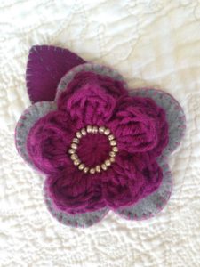 Grey and purple hand stitched felt and crocheted flower brooch.