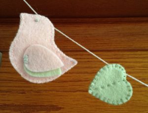 Pastel pink and green, hand sewn felt bird and heart.