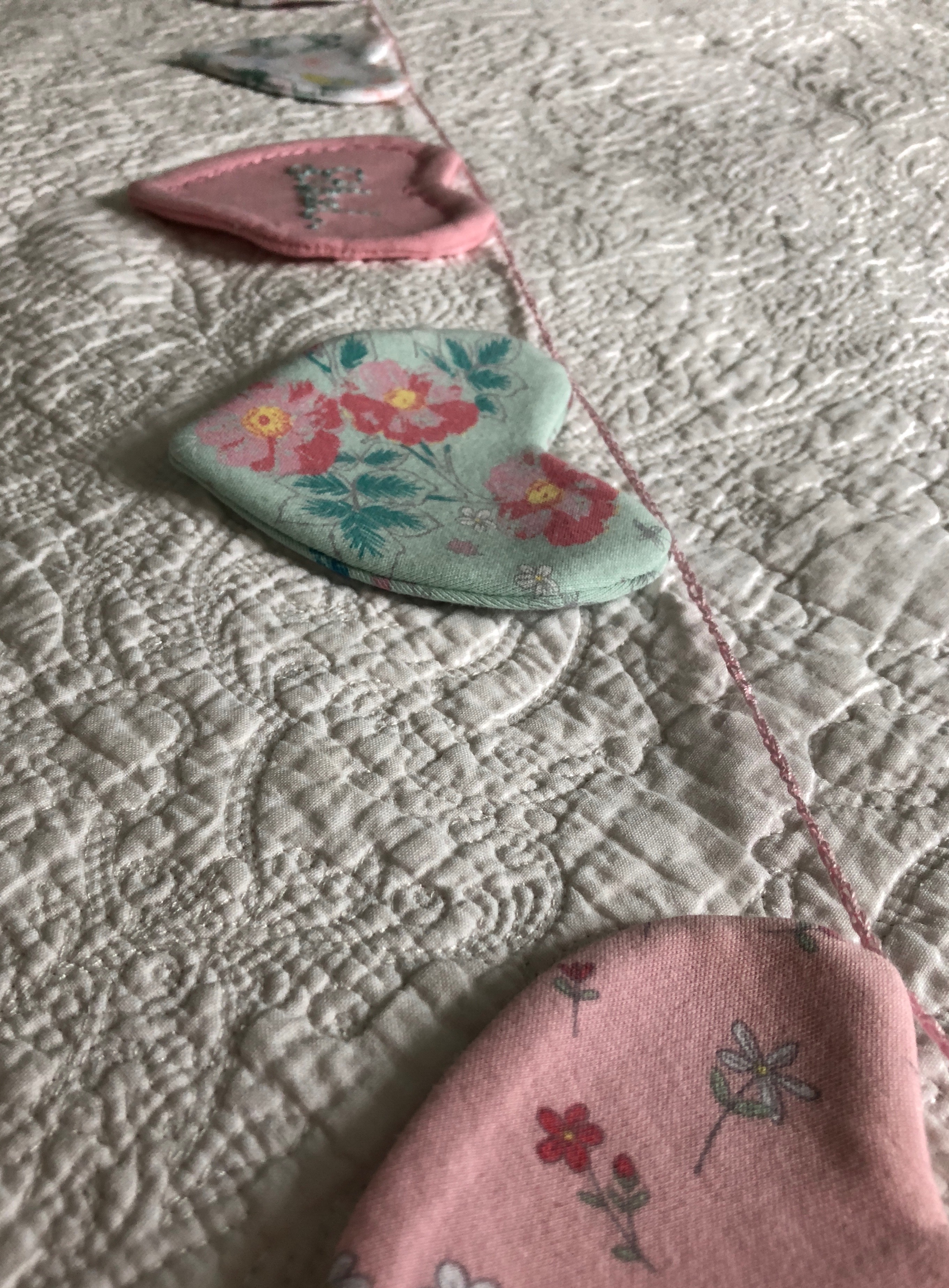 A keepsake hand embroidered heart garland made using a loved ones clothes.