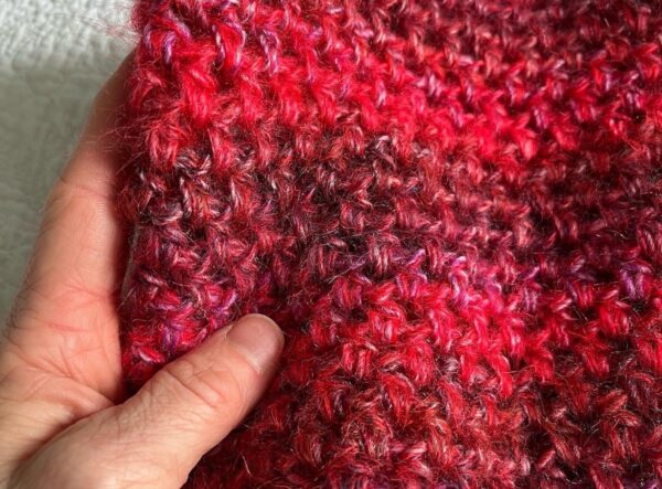 A handmade, crocheted neck warmer, in a variegated colour combination of red and purple tones. Made using a mix of two lightweight yet warm yarns. Acrylic/Wool/Mohair mix.