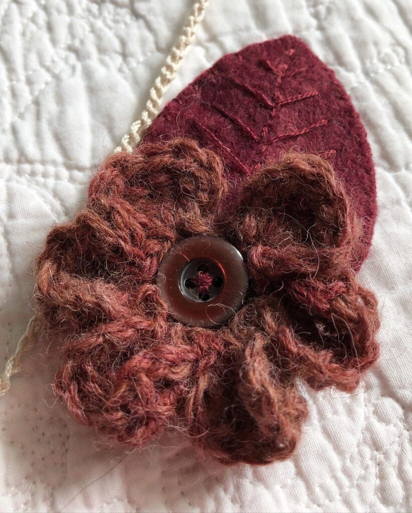 Handmade using 100% Alpaca wool and felt garland. A handmade, crocheted and sewn flower and leaf garland in a range of tonal hues. Burgundy through to Navy Blue. Seven Flower and leaf decorations along the garland.