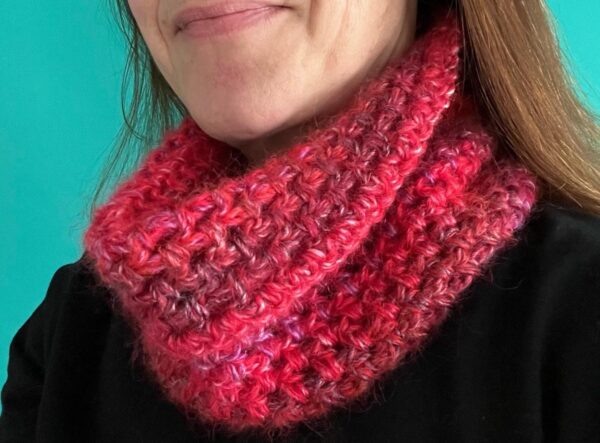 A handmade, crocheted neck warmer, in a variegated colour combination of red and purple tones. Made using a mix of two lightweight yet warm yarns. Acrylic/Wool/Mohair mix.