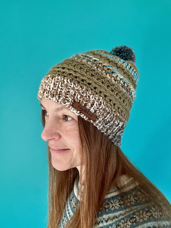 A soft and chunky textured hat with a large detachable bobble. Made in a khaki green yarn and a complimentary mix of cream, brown, grey and turquoise. Both yarns are very soft and chunky, yet lightweight and warm. The yarn is made of 100% Acrylic which makes it extremely wearable and machine washable too. The label is made from 100% Polyurethane so is Vegan friendly. This item is machine washable on a warm hand wash setting at 40c. Gently re-shape and dry flat. Do Not tumble dry. Do NOT iron.