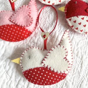 A hand cut and hand stitched, felt and fabric bird, with a red ribbon hanging loop and wooden heart button detail. Robins approximate size 8cm w x 5cm h. (excluding hanging ribbon.) This is a decoration only, and is NOT a toy. Keep out of the reach of babies and small children due to the small parts.