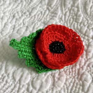 A small, double layered, red Poppy with black glass beaded detail and a green leaf. Handmade using 100% cotton, glass beads and a metal locking fastening on the back. Approximate size 6cm x 4cm.