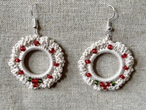 Hand made, crocheted, mini wreath earrings. Made using 100% cotton in natural cream colour with a mix of red and green glass beaded details. The earring hooks are made from a silver plated brass and are nickel, lead and cadmium free. Each earring measures approximately 3.5cm wide by 5.5cm Height (including hook).