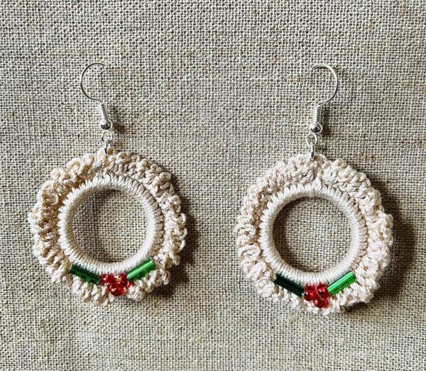 Hand made, crocheted, mini wreath earrings. Made using 100% cotton in natural cream colour with a mix of red and green glass beaded details. The earring hooks are made from a silver plated brass and are nickel, lead and cadmium free. Each earring measures approximately 3.5cm wide by 5.5cm Height (including hook).