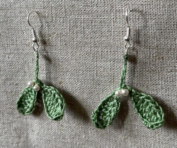 Hand made, crocheted, mini mistletoe earrings. Made using 100% cotton in soft green colour with glass pearl effect beaded details. The earring hooks are made from a silver plated brass and are nickel, lead and cadmium free. Each earring measures approximately 3cm wide by 5cm Height (including hook).