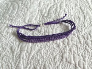 A handmade, crocheted and glass beaded bracelet. Fully adjustable with sliding metal bead fastening. 4 strands, made using 100% purple cotton and glass beads in 4 shades of purple.