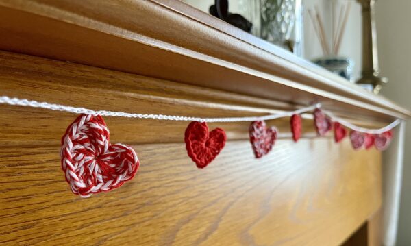 A garland of 11, red and white and solid red crocheted cotton hearts, on a white cotton chain.