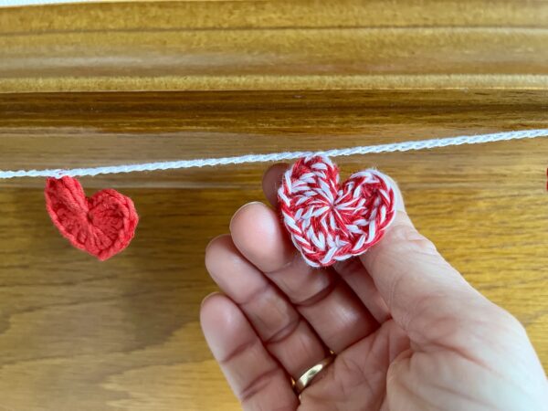 A garland of red and white and solid red crocheted cotton hearts, on a white cotton chain.