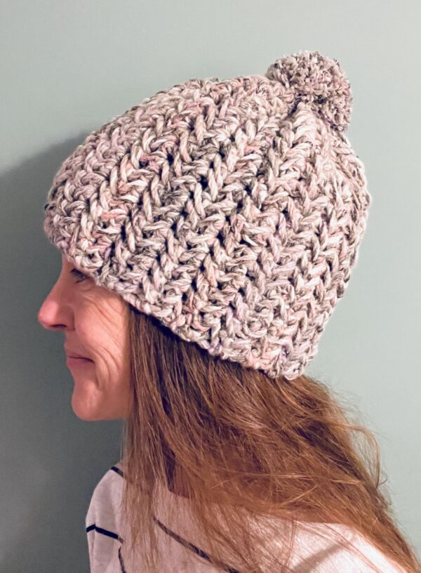 A chunky and thick textured hat with a large detachable bobble. Made using a yarn that combines a mix of soft grey, cream, pink and lilac. This super chunky yarn is made of 60% acrylic, 25% Cotton and 15% Wool mix. The perfect winter warmer! It is machine washable on a wool cycle at 40 degrees. Gently reshape whilst wet. Do not wring or spin.