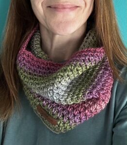 A loose fitting infinity scarf made using a soft and lightweight yarn in a mix of subtle heather colours of Purple, pink, grey, green.