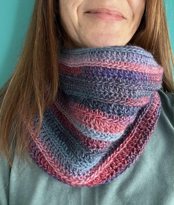 A handmade, soft textured, crocheted neck warmer, made using a soft and lightweight acrylic/wool mix yarn in shades of pinks and blues.