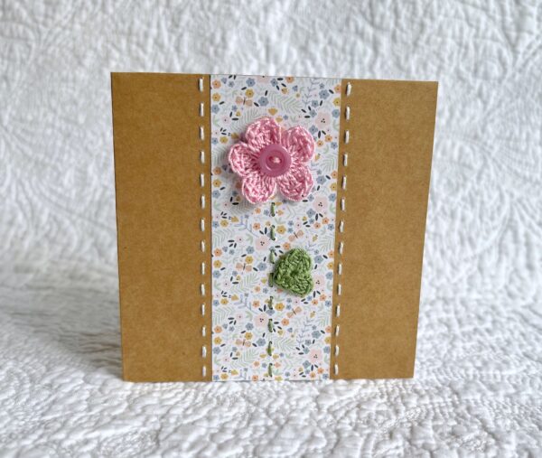 A single crocheted flower and leaf, with a hand stitched border. This small brown card has a blank white insert for your own message, and an envelope is included. Approximate size 10cm x 10 cm. Made using 100% cotton. Eco-friendly, Vegan friendly and fully recyclable.