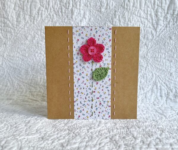 A single crocheted flower and leaf, with a hand stitched border. This small brown card has a blank white insert for your own message, and an envelope is included. Approximate size 10cm x 10 cm. Made using 100% cotton. Eco-friendly, Vegan friendly and fully recyclable.