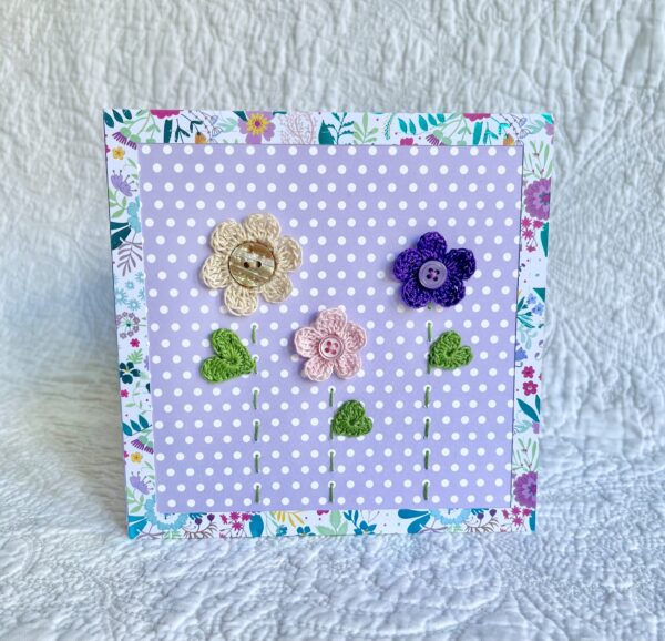 A trio of crocheted flowers and leaves, with buttons and hand stitched details. This spotty card has a blank white insert for your own message, and an envelope is included. Approximate size 15cm x 15 cm. Made using 100% cotton. Eco-friendly, Vegan friendly and fully recyclable.