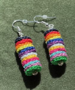 A handmade, crocheted pair of earrings made of multicoloured discs, made using 100% cotton and glass beads and metal fixings. The earring hooks are made from a silver plated brass and are nickel, lead and cadmium free. Each earring measures approximately 1.2cm wide by 5cm Height (including hook). No plastic has been used. This item is Vegan and Eco-friendly, reusable and fully recyclable.