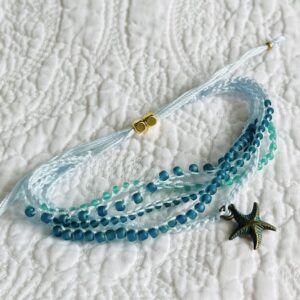 A 5 stranded, handmade and crocheted bracelet. Fully adjustable and made using glass and metal beads with antique brass coloured metal starfish charm. Made from 100% Cotton, glass and metal beads and a metal charm. No plastic! Eco-friendly, vegan friendly and completely recyclable.