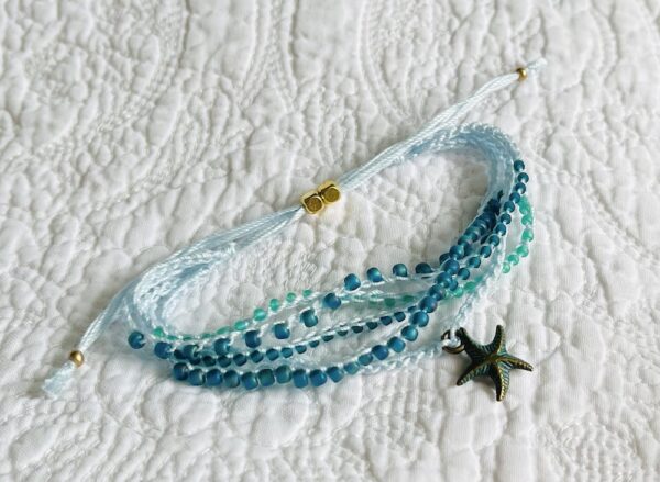 A 5 stranded, handmade and crocheted bracelet. Fully adjustable and made using glass and metal beads with antique brass coloured metal starfish charm. Made from 100% Cotton, glass and metal beads and a metal charm. No plastic! Eco-friendly, vegan friendly and completely recyclable.