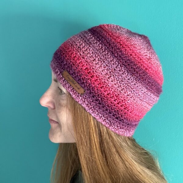 A soft and delicate textured beanie style hat. Made in a vibrant mix of red, pink, and purple shades, using a very soft and lightweight Acrylic yarn.