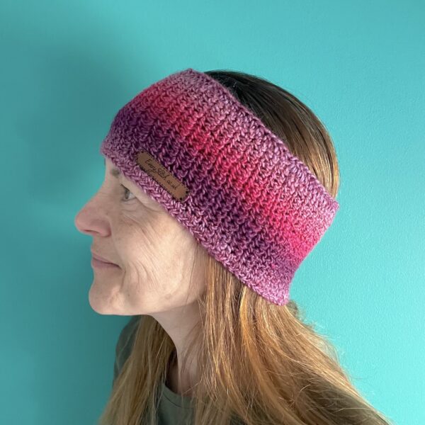 A soft and delicate textured ear warmer/head band. Made in a vibrant mix of red, pink, and purple shades, using a very soft and lightweight Acrylic yarn.